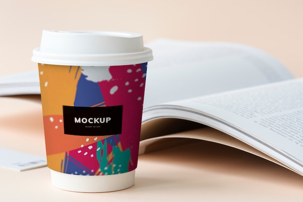 Takeaway coffee cup mockup on a table with an open book