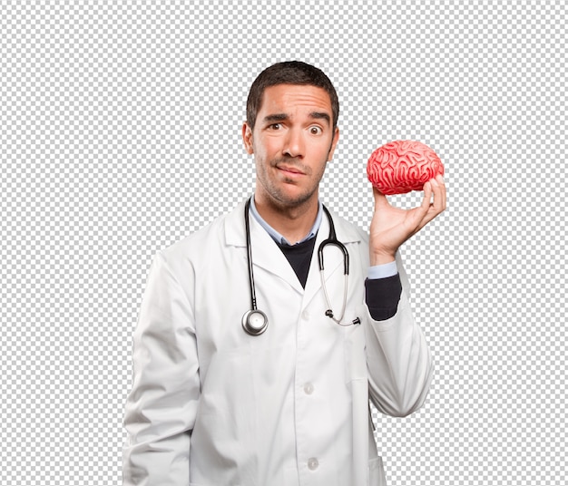 PSD thoughtful doctor holding a toy brain against white background