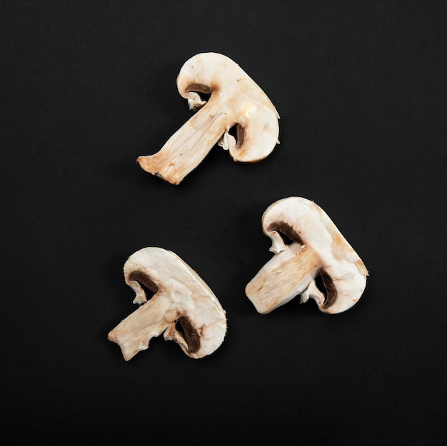 Three pieces of button mushrooms on black background