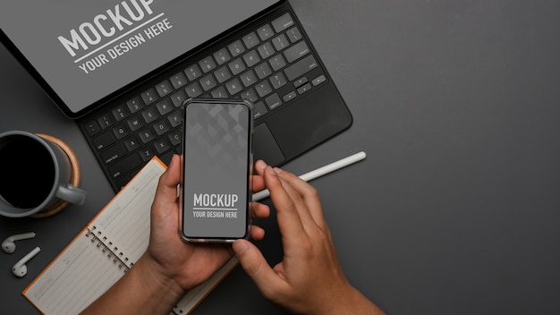 Top view of male hand using smartphone mockup while working with tablet