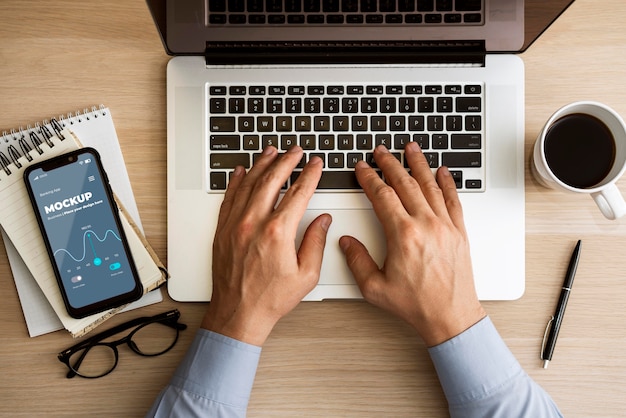 PSD top view man using laptop near phone mock-up