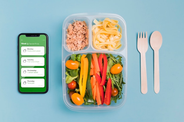 Top view of meal with vegetables and smartphone