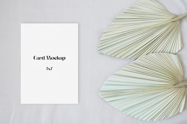 Top view mockup wedding card with leaf palm on the beige background