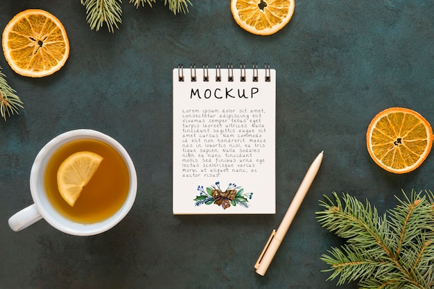 Top view of notepad with spruce branches and tea