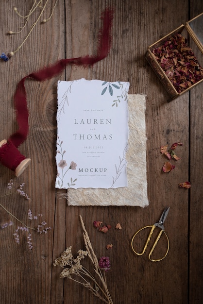 Top view of paper mock-up rustic wedding invitation with leaves and flowers