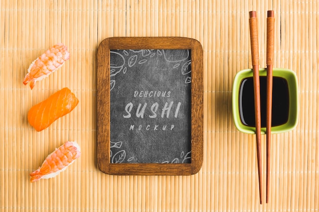 Top view of sushi with chopsticks and blackboard