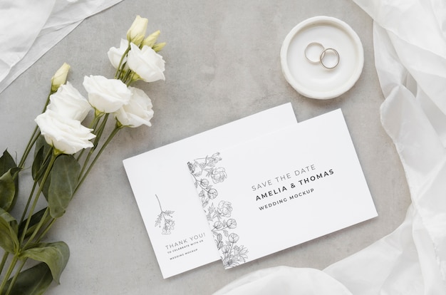 Top view of wedding cards with rings and roses