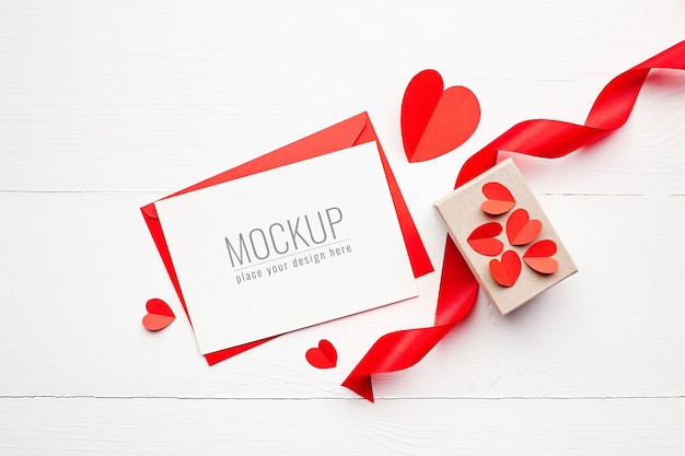 Valentine's day card mockup with gift box, red ribbon and paper hearts