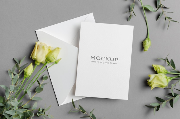 Wedding invitation card mockup with white envelope and flowers on grey