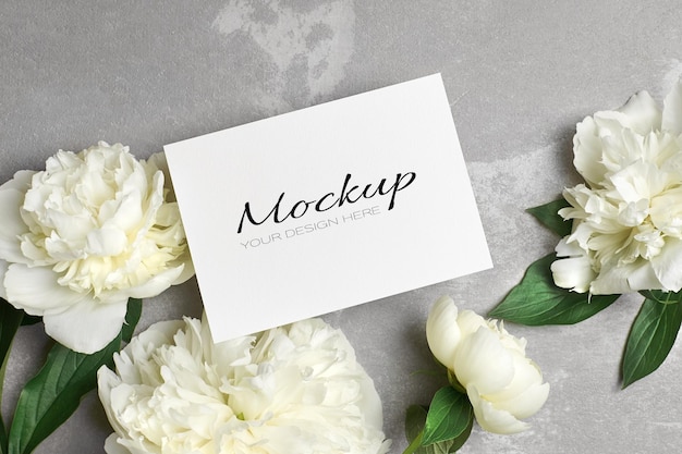 Wedding invitation or greeting card mockup with envelope and white peony flowers on grey