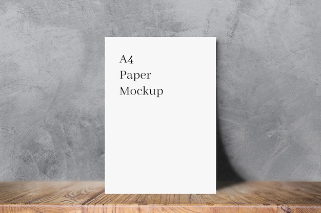 White A4 Paper Mockup on Wood Leaning on Concrete Texture Background