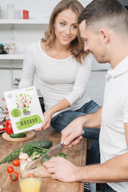 PSD woman holding book in the kitchen while man cooks