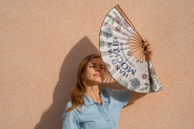 Woman holding hand fan with mock-up design