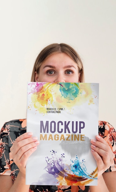 Woman holding a mock up magazine and looking at camera