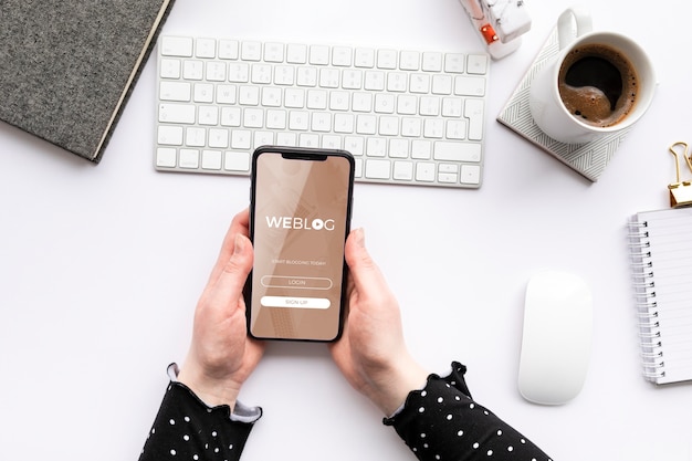 Woman holding phone mock-up at desk