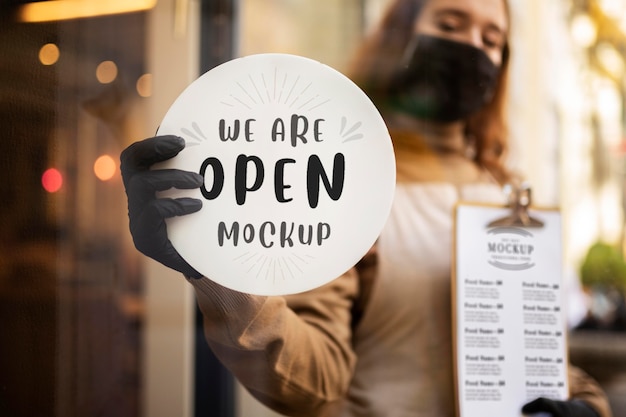 Woman holding a restaurant we are open sign