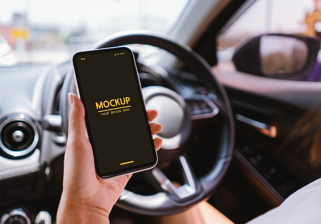 Woman holding smartphone mockup in the car