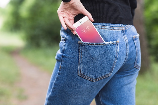 Woman in nature with smartphone in pocket