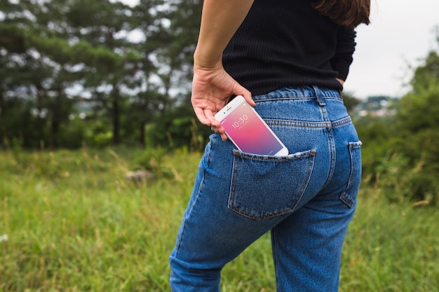 Woman in nature with smartphone in pocket