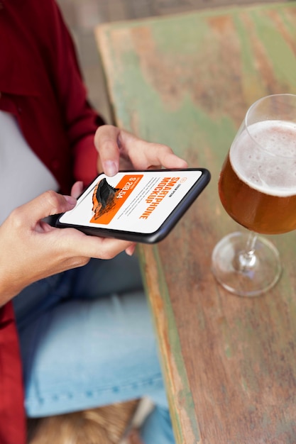 Woman using mock-up smartphone outdoors with a glass of drink