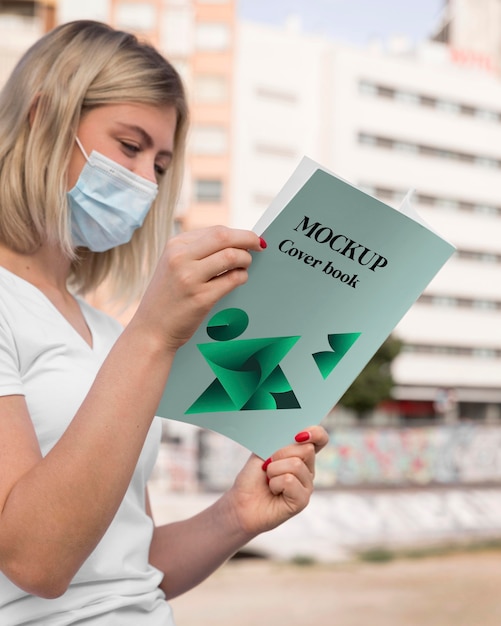 Woman with mask reading book on street