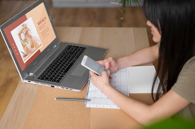 Woman working from home using laptop and smartphone