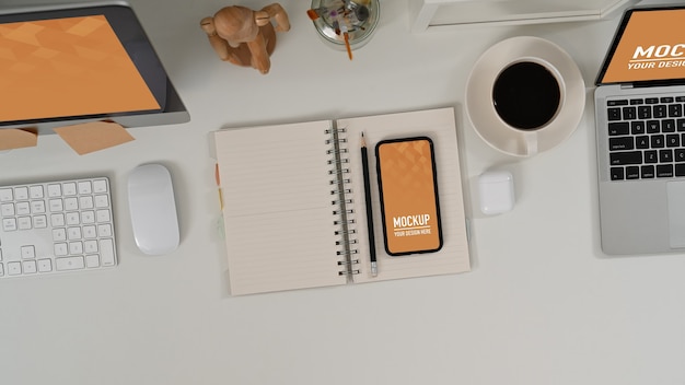 Workspace with black screen smartphone and office supplies on white table