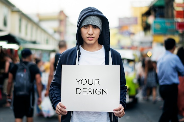 PSD young asian man holding empty placard outdoors