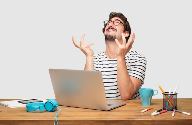 young bearded graphic designer with a laptop and confused look