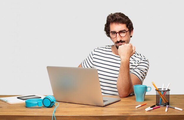 young bearded graphic designer with a laptop looking proud, confident and powerful