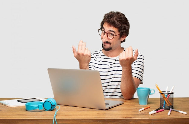 young bearded graphic designer with a laptop smiling with a proud, satisfied and happy look