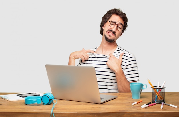 young bearded graphic designer with a laptop with an anxious, stressed and nervous gesture