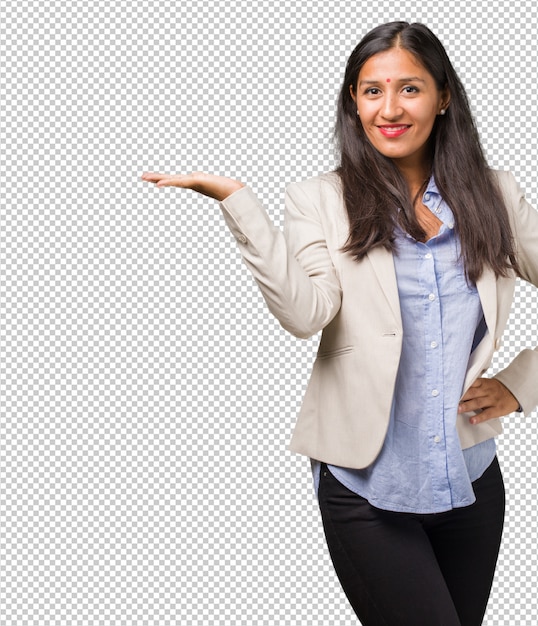 Young business indian woman holding something with hands, showing a product, smiling and cheerful, offering an imaginary object