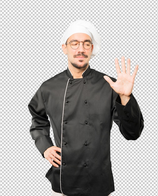 Young chef making a number five gesture