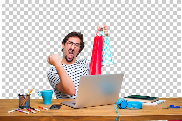 PSD young crazy graphic designer on a desk with a laptop and with shopping bags