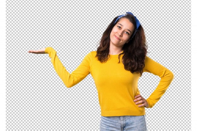 Young girl with yellow sweater and blue bandana on her head holding copyspace