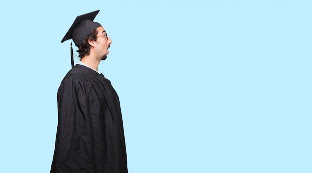 young graduated man smiling and looking upwards, towards the sky