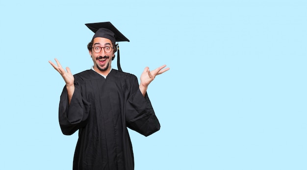 young graduated man with a happy surprised expression, eyes wide open and broad smile