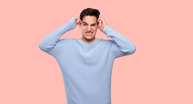 PSD young handsome man shouting with a crazy, amazed look of surprise, holding head with both hands