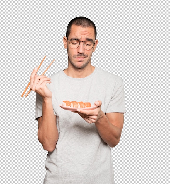 Young man using chopsticks to eat sushi