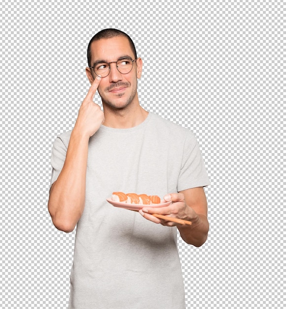 Young man using chopsticks to eat sushi