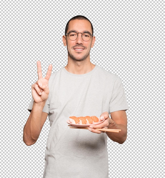 Young man using chopsticks to eat sushi