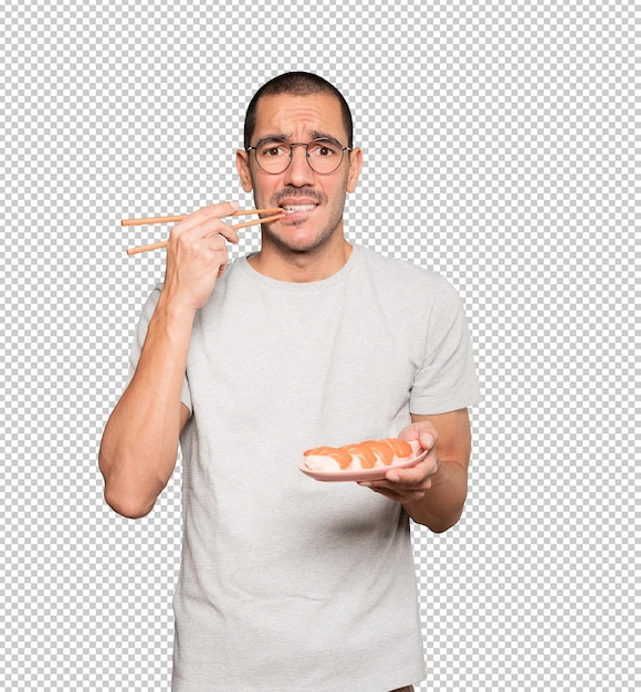 Young man using chopsticks to eat sushi