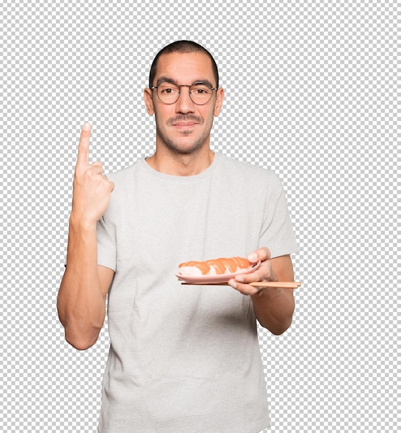 Young man using chopsticks to eat sushi