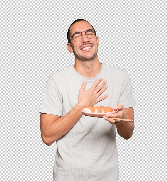 Young man using chopsticks to eat sushi