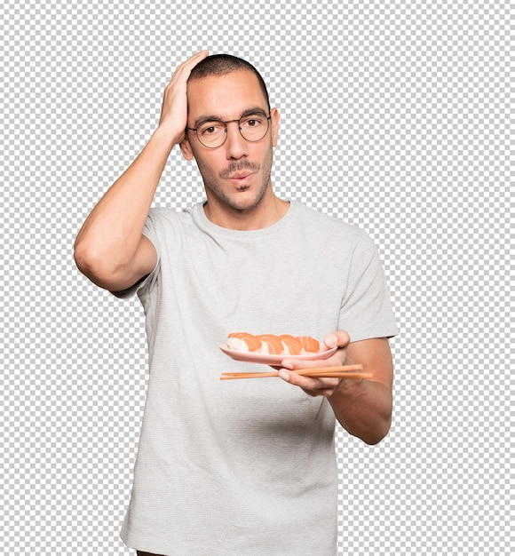 Young man using chopsticks to eat sushi