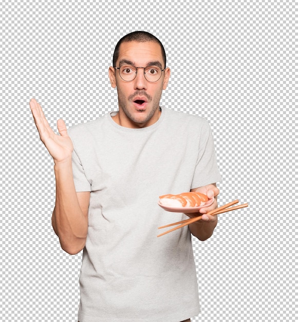 Young man using chopsticks to eat sushi