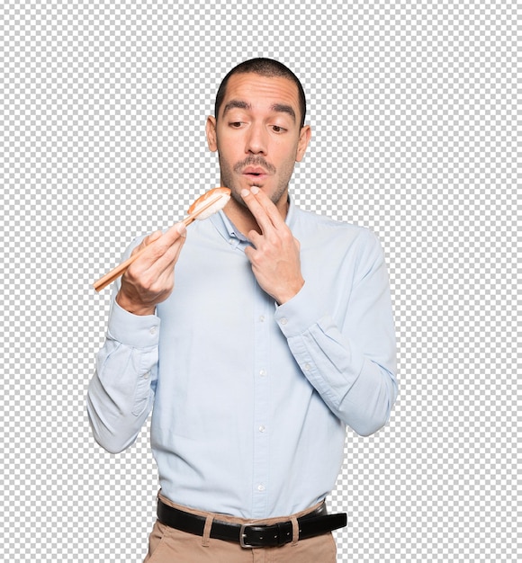 Young man using chopsticks to eat sushi