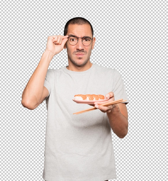 Young man using chopsticks to eat sushi