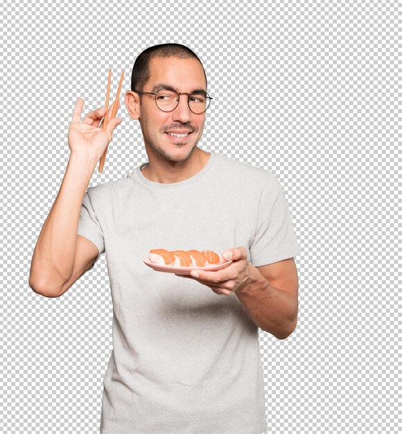 Young man using chopsticks to eat sushi